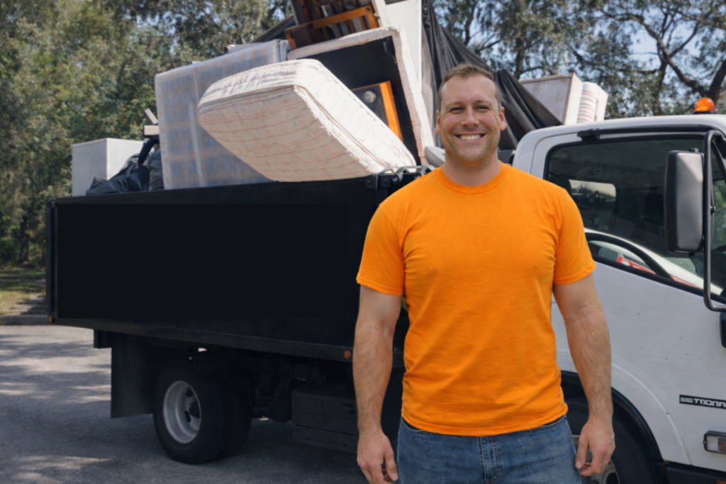 Haul Helper standing in front of a truck full of junk